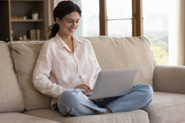 istock Cheerful freelancer woman working at laptop on home couch 1407759014