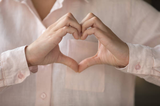 istock Young woman making finger heart shape, joining hands at chest 1407759042