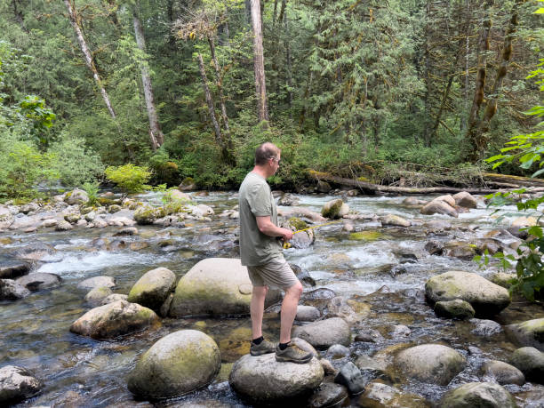 istock Mature man fishing on small stream for trout 1407759070