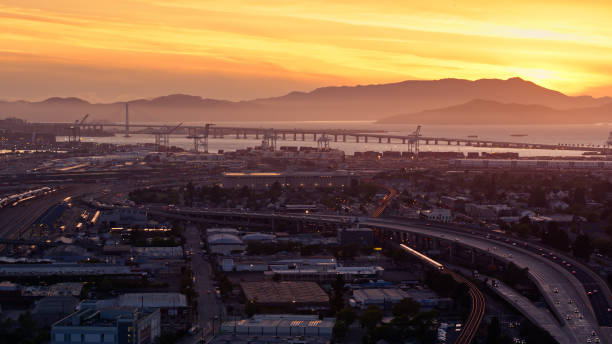 サンセットのフリーウェイと鉄道横断ウェストオークランドのドローンショット - oakland california commercial dock harbor california ストックフォトと画像