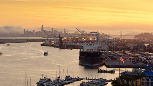 traghetto e nave portacontainer a inner harbor a oakland, california al tramonto - aerial - passenger ship ferry crane harbor foto e immagini stock