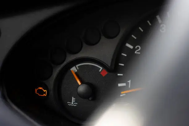 Photo of Yellow lit engine error sign on car dashboard close up