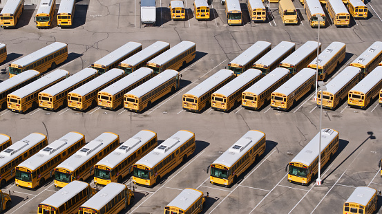 Aerial shot of a yard full of yellow school buses in Vail, a suburb southeast of Tucson in Pima County, Arizona on a hazy day in spring.