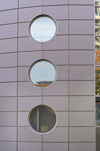 Three round windows at modern gray building wall