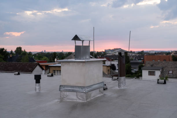 Flat roof covered with bitumen membrane and silver lacquer with chimney on a private house. Sunset in city in bg
