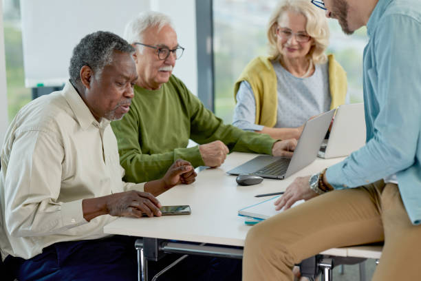 istock A young professor is sitting on a desk in a classroom and explaining lesson to multicultural senior students. 1407765948
