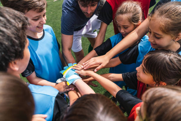 giocatori di calcio di bambini femminili e maschi insieme con le mani in cerchio prima di una partita - categoria juniores foto e immagini stock