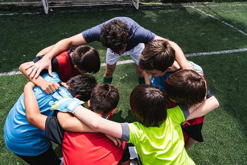 Kids soccer team huddling together on a soccer field