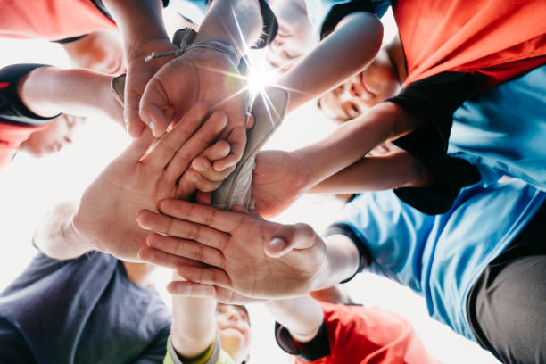 low-winkel-ansicht der kinder fußball-schulteam huddling zusammen - contest togetherness human hand unity stock-fotos und bilder