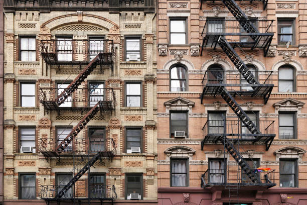 Old fashioned Manhattan apartment building facade with ornate decorative stone carving and external fire escape ladders stock photo