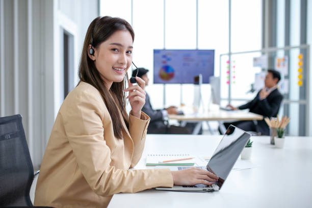 istock female operator agent with headsets and her team working in a call center customer service office. Asian employee woman working with a headset, Customer support. 1407787535