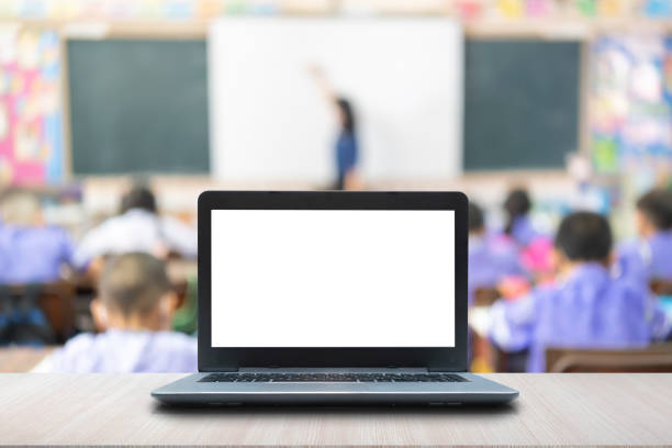 istock Computer on the table, blur image of children in the classroom as background. 1407793860
