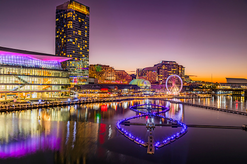 Fountain floating on waters of Darling Harbour in Sydney at Vivid Sydney ligth show - sunset cityscape.