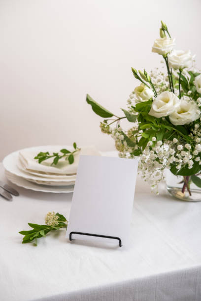 istock Mockup white blank space card for table number or menu. Wedding teble decoration with white flowers, glasses and white napkins. Elegantly decorated table at a wedding reception. Festive table setting. The wedding decor. 1407797846