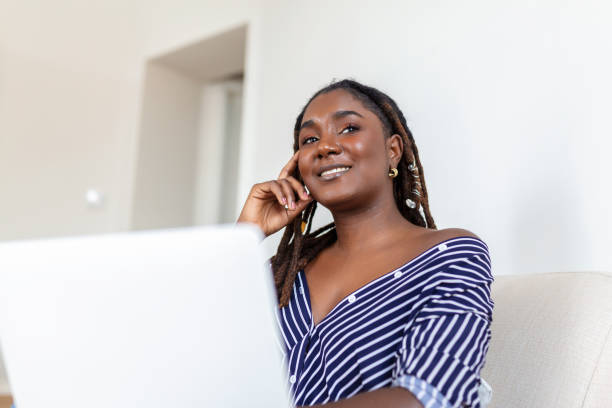 istock Nice beautiful African woman work at the notebook on the sofa at home - check on oline shops for cyber monday sales - technology woman concept for alternative office freelance 1407799035