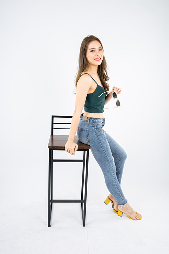 Attractive asian young woman sitting in bar chair on white background.