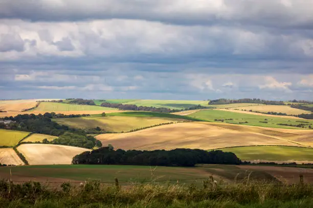 Patches of afternoon sunlight hitting the farmland of the south downs from Newmarket hill near Woodingdean, Brighton, East Sussex, south east England