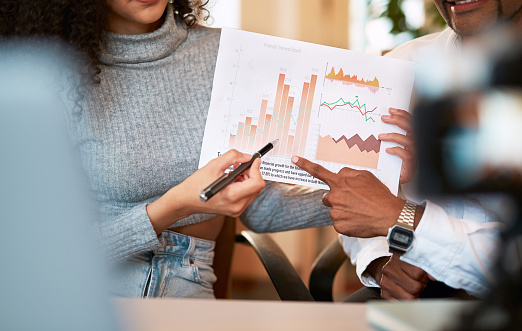 A group of people in meeting doing some discussion in graph. office meeting. Busy working day. Business professionals. Group of young confident business people analyzing data using graph while spending time in the office.