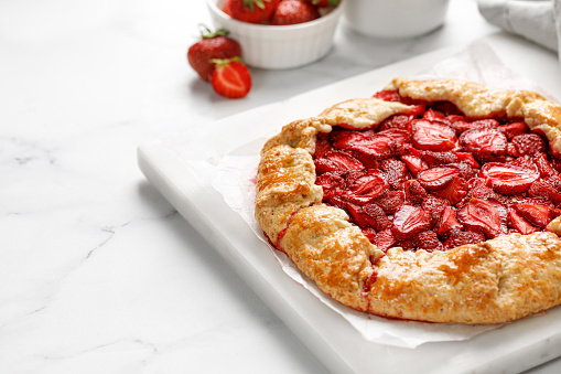 Open strawberry pie on marble board. Strawberry galette. Homemade pastry, baked cake with strawberry. Copy space, text.