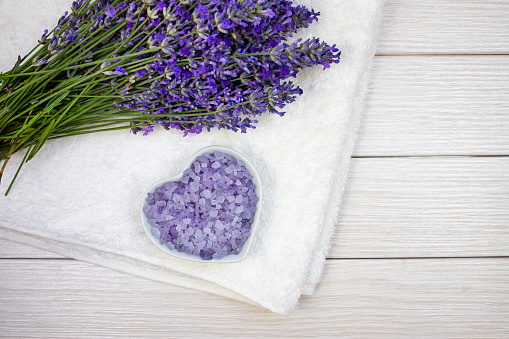 Natural lavender flowers with bath salt on white towel. Skin care concept. View from above.