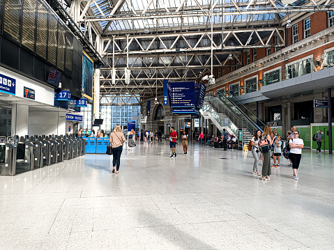 View of hall of Waterloo train station, terminal station for trains to South-West London and South England. Modern glass building. Lots of passengers inside of hall. Public transportation