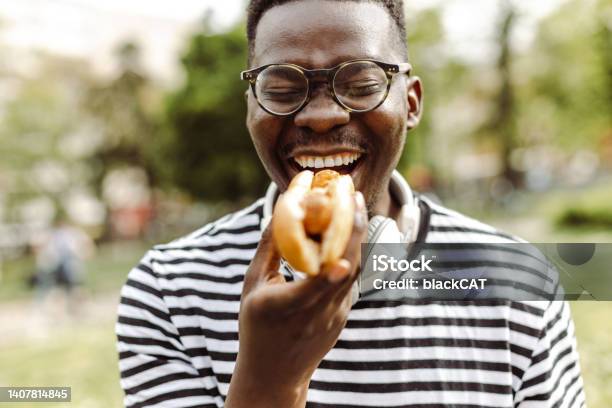 Close Up Portrait Of Young Man Eating Hot Dog Outdoors Stock Photo - Download Image Now