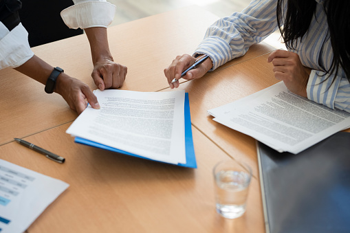 Shot of documents and female hands signing contracts at business table