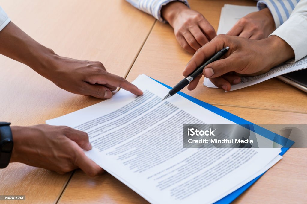 Close-up shot of hands holding and pointing with a pen at documents Close-up shot of hands holding and pointing at text in documents Contract Stock Photo