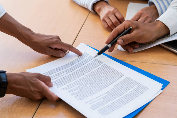 Close-up shot of hands holding and pointing with a pen at documents stock photo