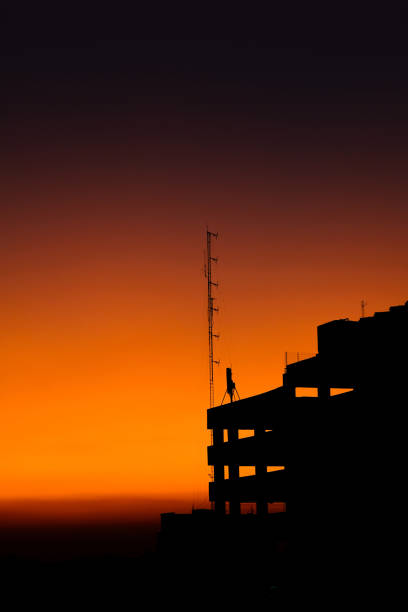 The silhouette of the parking building with a very beautiful orange sunset background with the sky starting to darken. vertical picture.