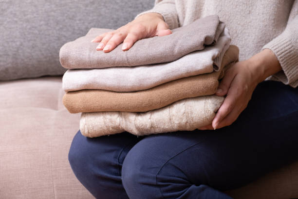 istock Female hands stack cozy knitted sweaters on the sofa. Warm concept 1407817717