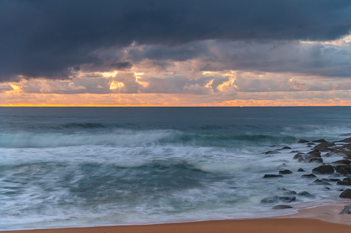Sunrise at the seaside with rain clouds at Killcare Beach on the Central Coast, NSW, Australia.