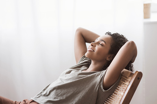 African american girl daydreaming. Woman relaxing in chair at home. Relaxation, resting, leisure, lockdown, self care, enjoy life concept