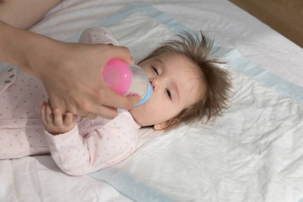 istock Newborn lying on bed drink breast milk from bottle 1407824528