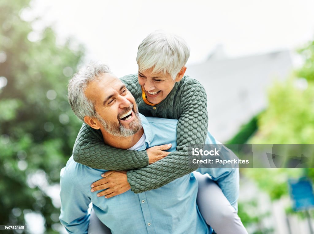 woman man outdoor senior couple happy lifestyle retirement together smiling love piggyback active mature Happy active senior couple outdoors Couple - Relationship Stock Photo