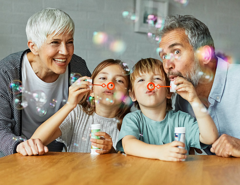 Portrait of grandparents and grandchildren having fun  blowing soap  bubbles together at home