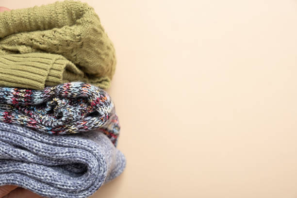 istock A stack of cozy knitted sweaters on beige background. Warm concept 1407824890