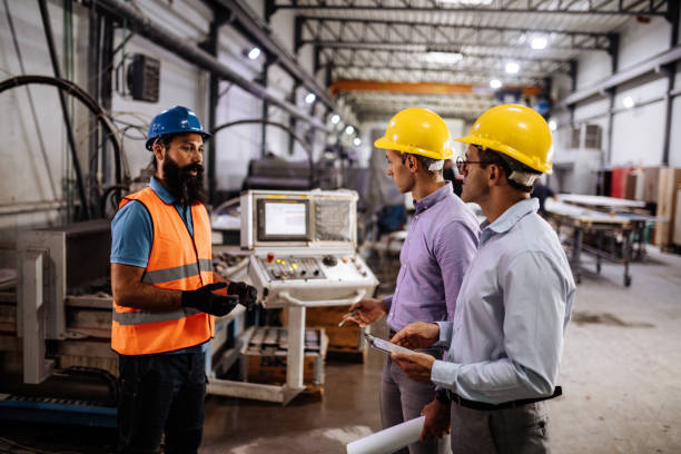 istock Engineers in factory hall, performing quality control. Manufacturing occupation in modern industrial hall, with automated process and robots. Metal processing industry and warehouse. 1407825841