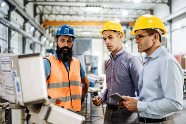istock Engineers in factory hall, performing quality control. Manufacturing occupation in modern industrial hall, with automated process and robots. Metal processing industry and warehouse. 1407825913