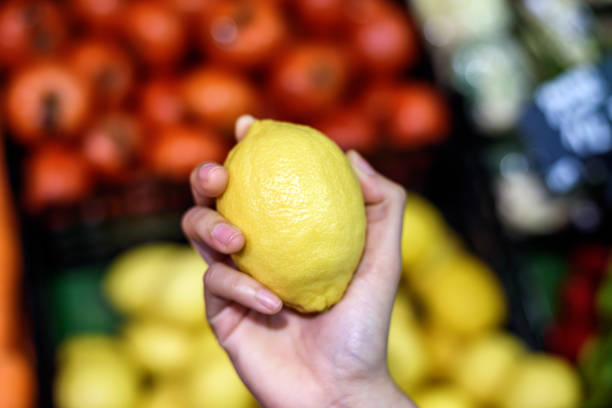 istock woman hand choosing fresh lemon fruit in supermarket 1407826202