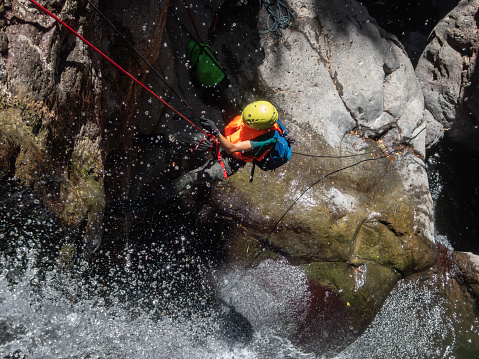 Qatsrin, Israel, June 11, 2022 : An experienced athlete descends with equipment for a rappel on a waterfall on the Black Gorge, Zavitan stream in the Golan Heights, near to Qatsrin, northern Israel