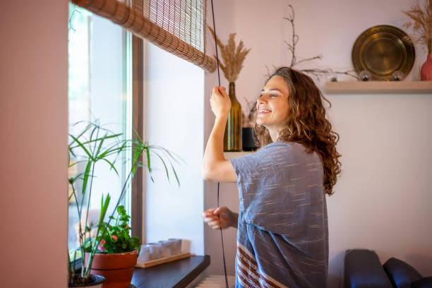 piękna szczęśliwa młoda kobieta otwierająca zwinięte bambusowe żaluzje w wiejskim domu w letni poranek - shutter wood window europe zdjęcia i obrazy z banku zdjęć