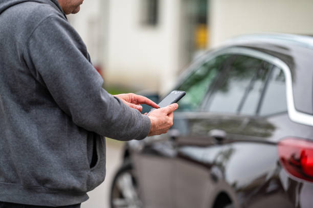 istock man with smartphone standing next to the car, using mobile app for paying, car lock  or Internet 1407829891