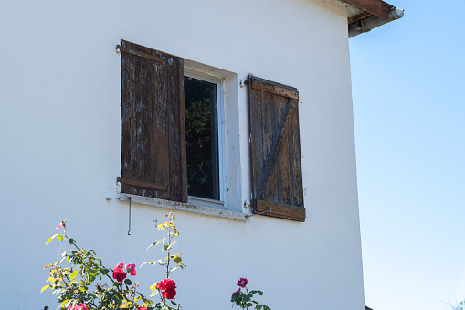 Wooden window with shutters open on and flowers in hanging flower tray