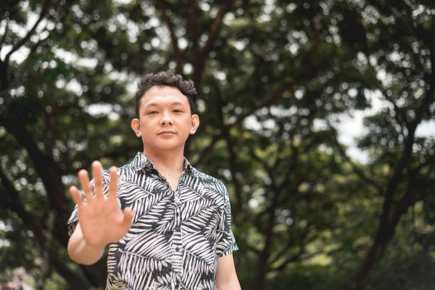 istock A young asian man refuses to cooperate, extending his hand out to make a stop gesture while looking stoically. 1407831595