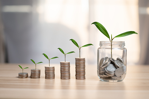 Business Investment and money saving ideas of people A graph of stacked coins A tree grows on coins and jars by saving money.