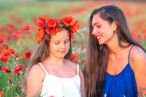 beautiful young woman with child girl in poppy field, happy family having fun in nature, summer time