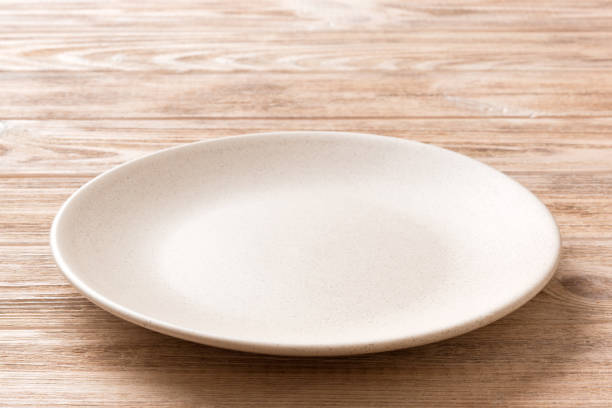 istock Perspective view of empty light plate on wooden background. Empty space for your design 1407834247