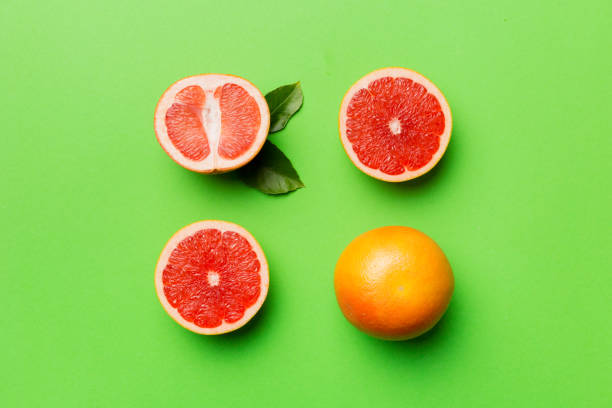 istock fresh Fruit grapefruit with Juicy grapefruit slices on colored background. Top view. Copy Space. creative summer concept. Half of citrus in minimal flat lay with copy space 1407834339