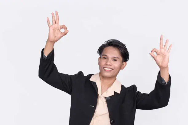 A confident and upbeat Filipino office employee with hands raised making a double OK gesture. Isolated on a white backdrop.